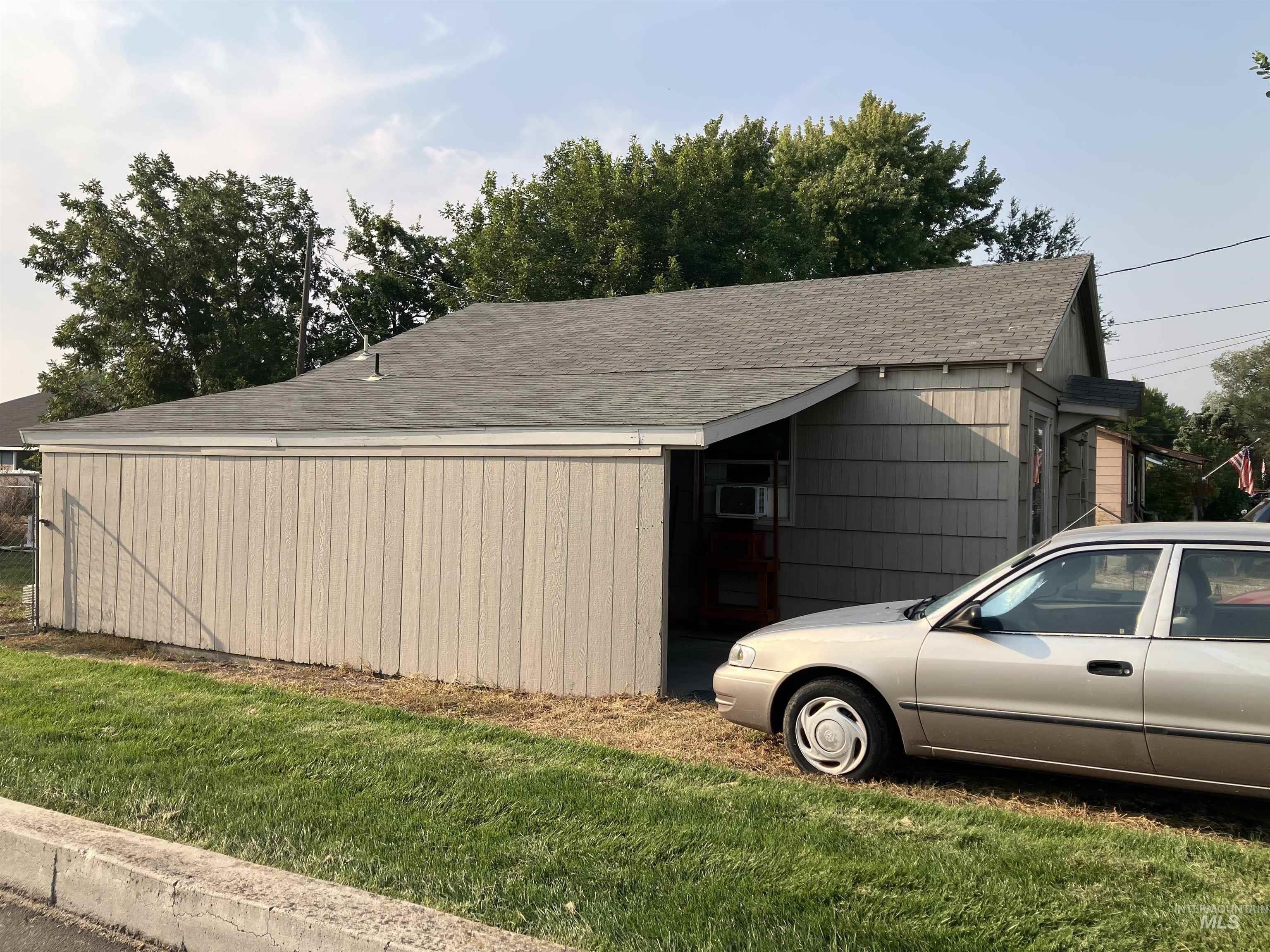 View of side of home with roof with shingles and a yard