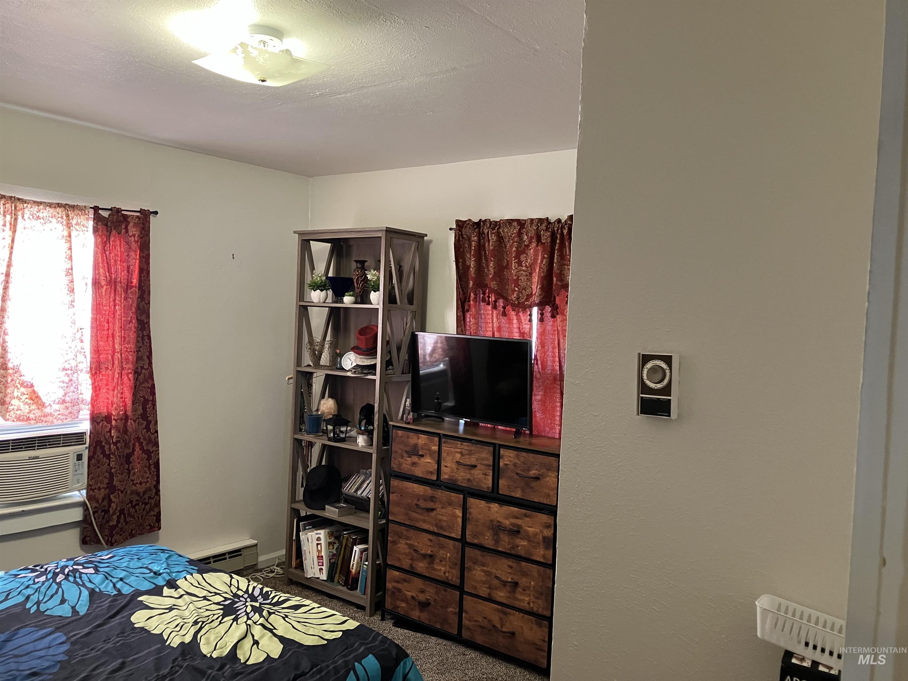 Bedroom featuring dark carpet, cooling unit, a textured ceiling, and baseboard heating