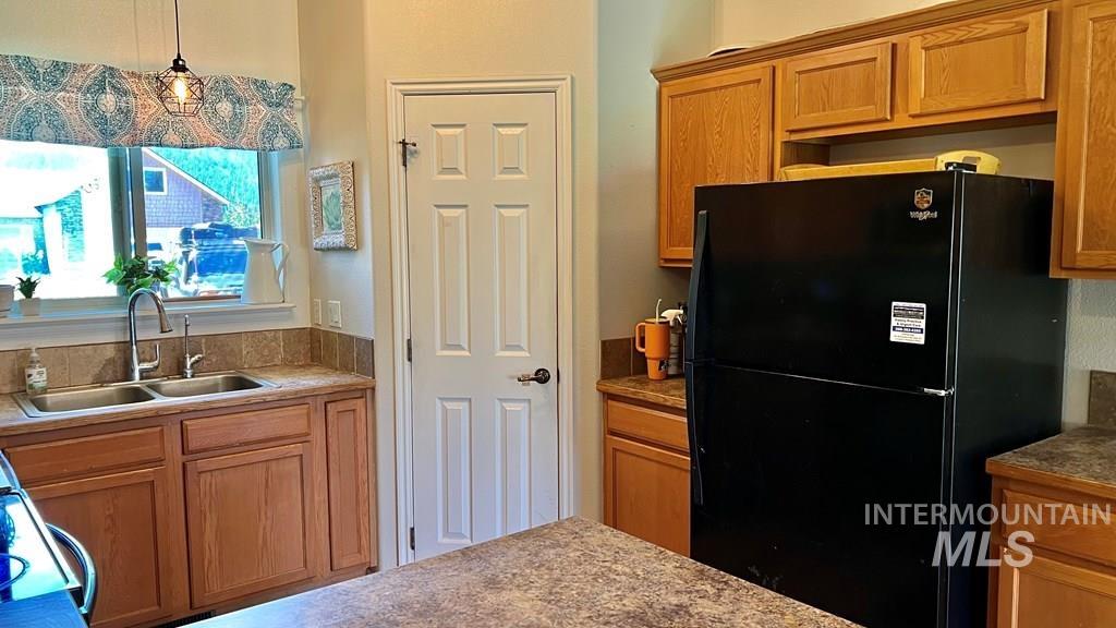 Kitchen with freestanding refrigerator, brown cabinets, decorative light fixtures, and electric stove