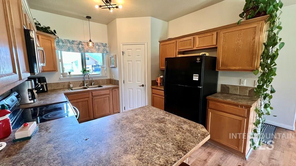 Kitchen featuring freestanding refrigerator, stainless steel microwave, brown cabinets, a peninsula, and range with electric cooktop