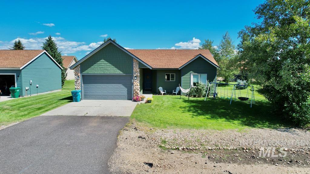 Ranch-style house featuring a front lawn, driveway, stone siding, and an attached garage