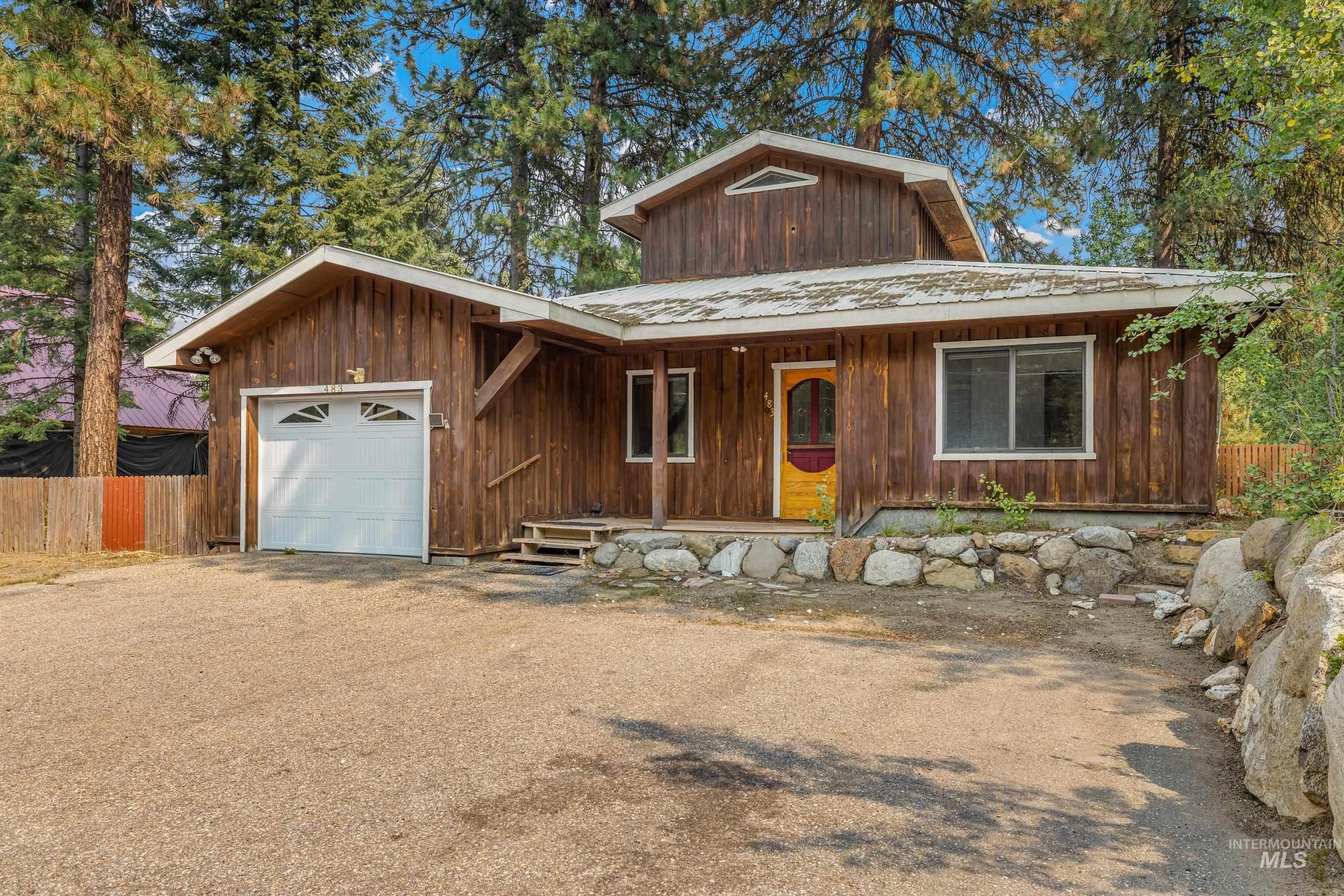 Chalet / cabin with a porch, a metal roof, a garage, and driveway