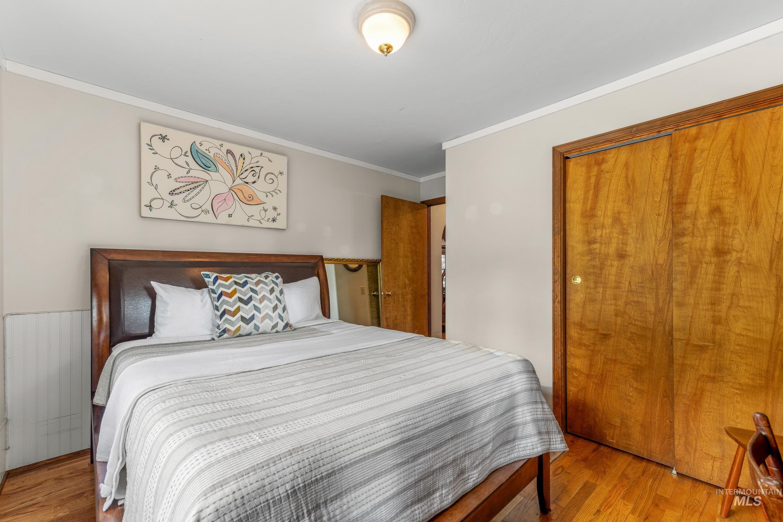 Bedroom featuring crown molding, wood finished floors, and a closet