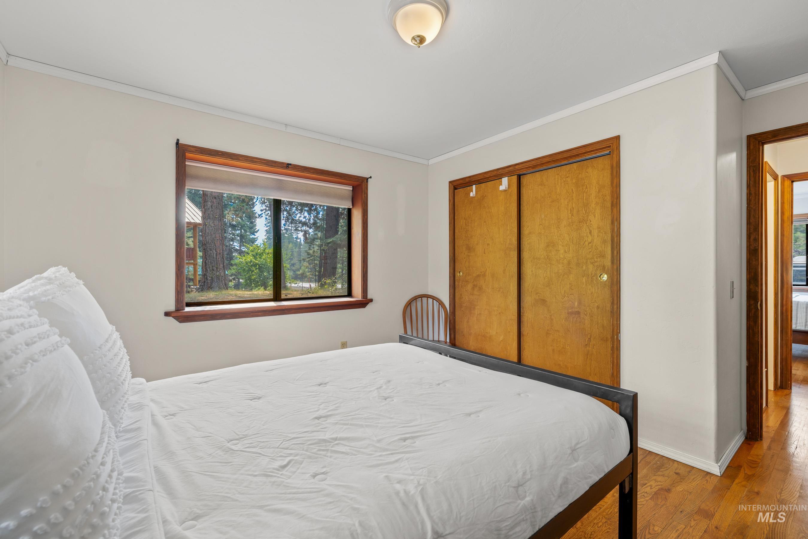 Bedroom featuring crown molding, wood finished floors, and a closet