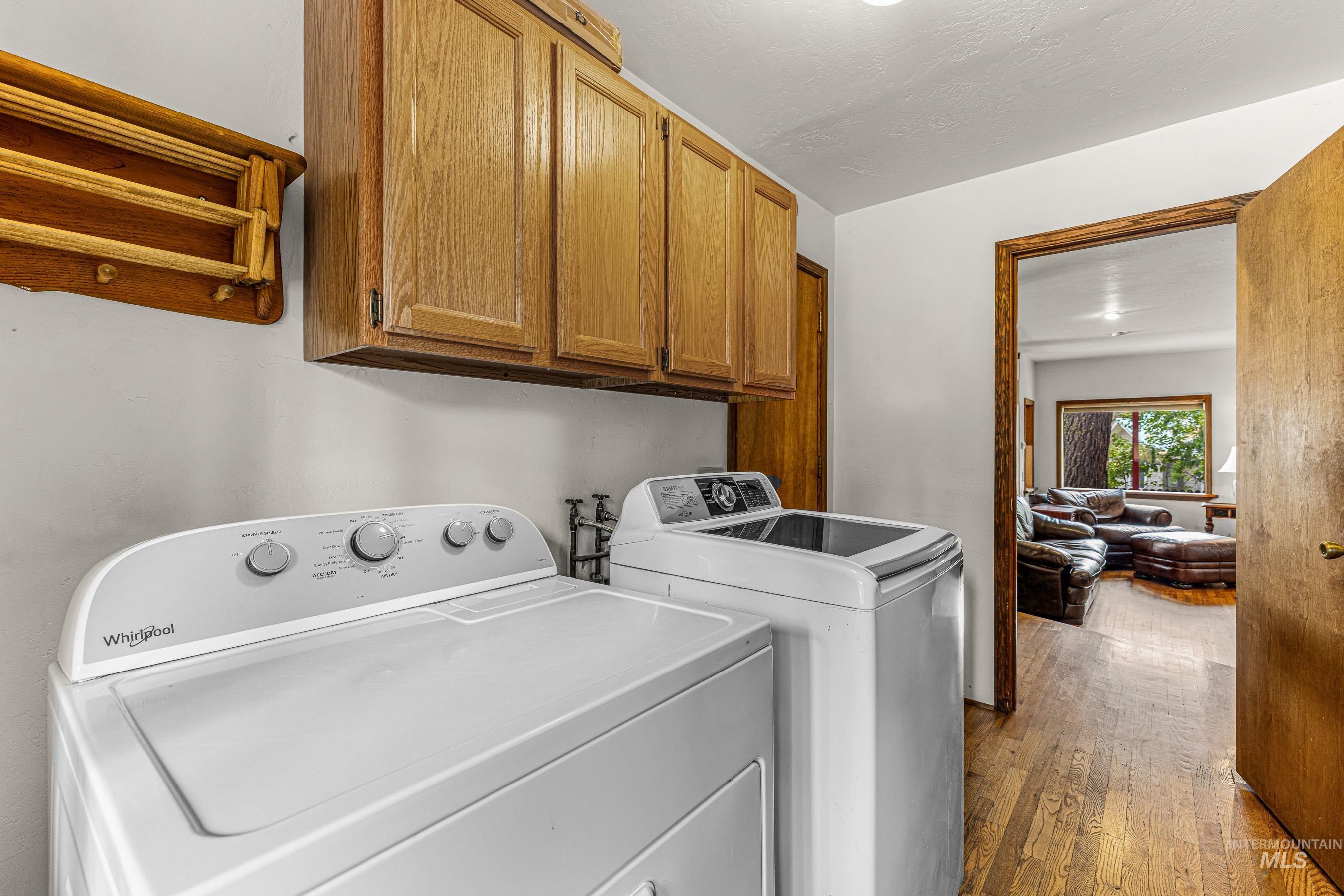Laundry area with dark wood-style floors, washing machine and clothes dryer, and cabinet space