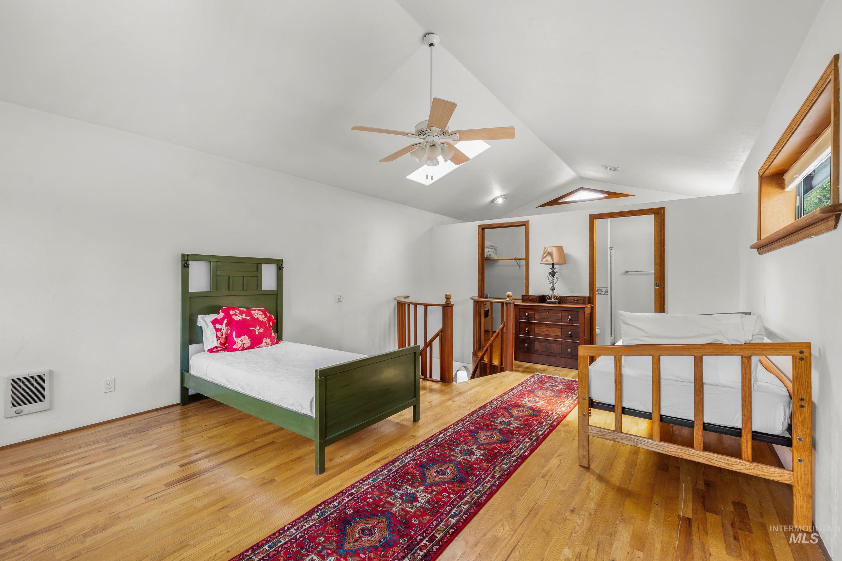 Bedroom featuring lofted ceiling, wood finished floors, a ceiling fan, and heating unit