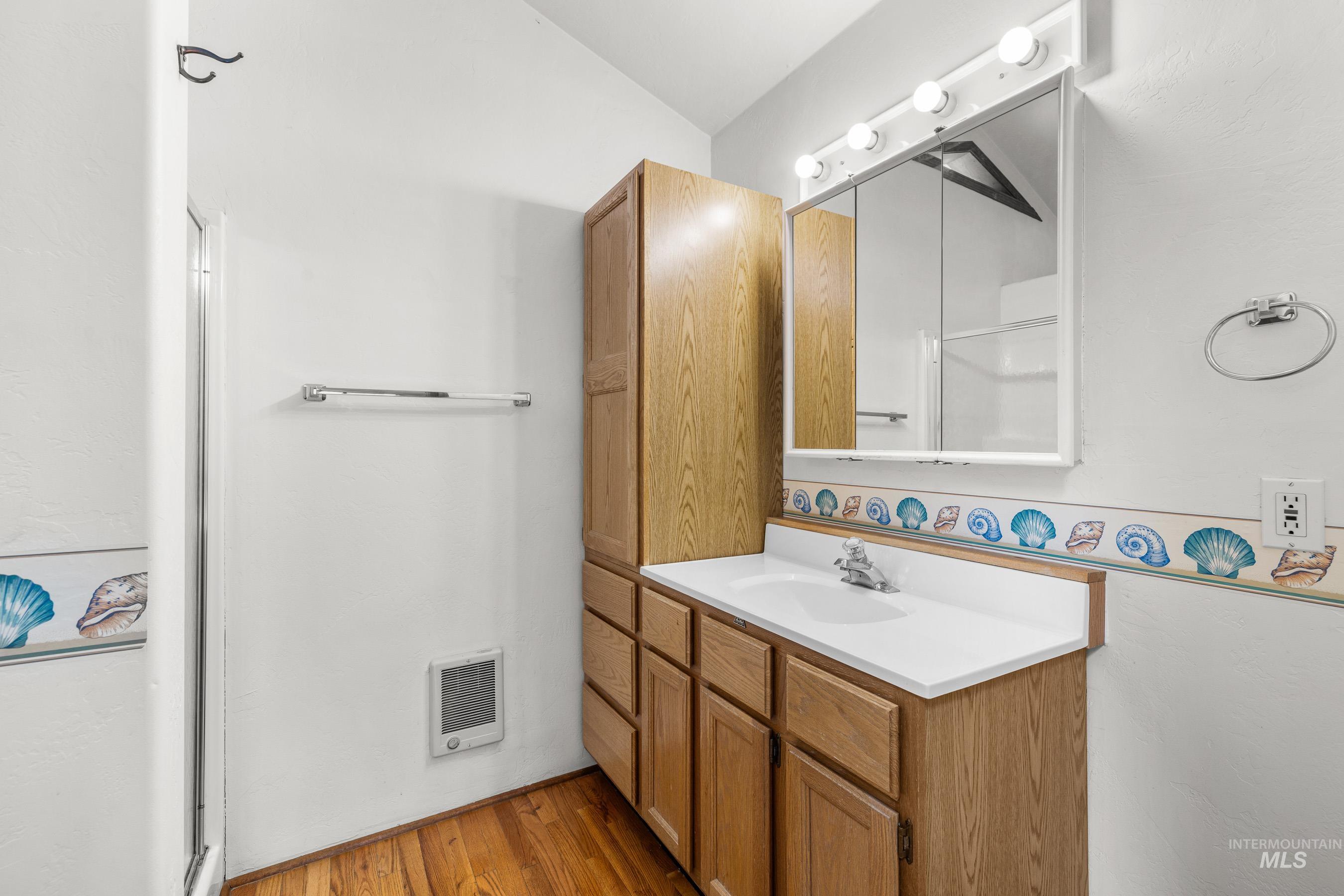 Full bath with a shower stall, vanity, light wood-style floors, and heating unit