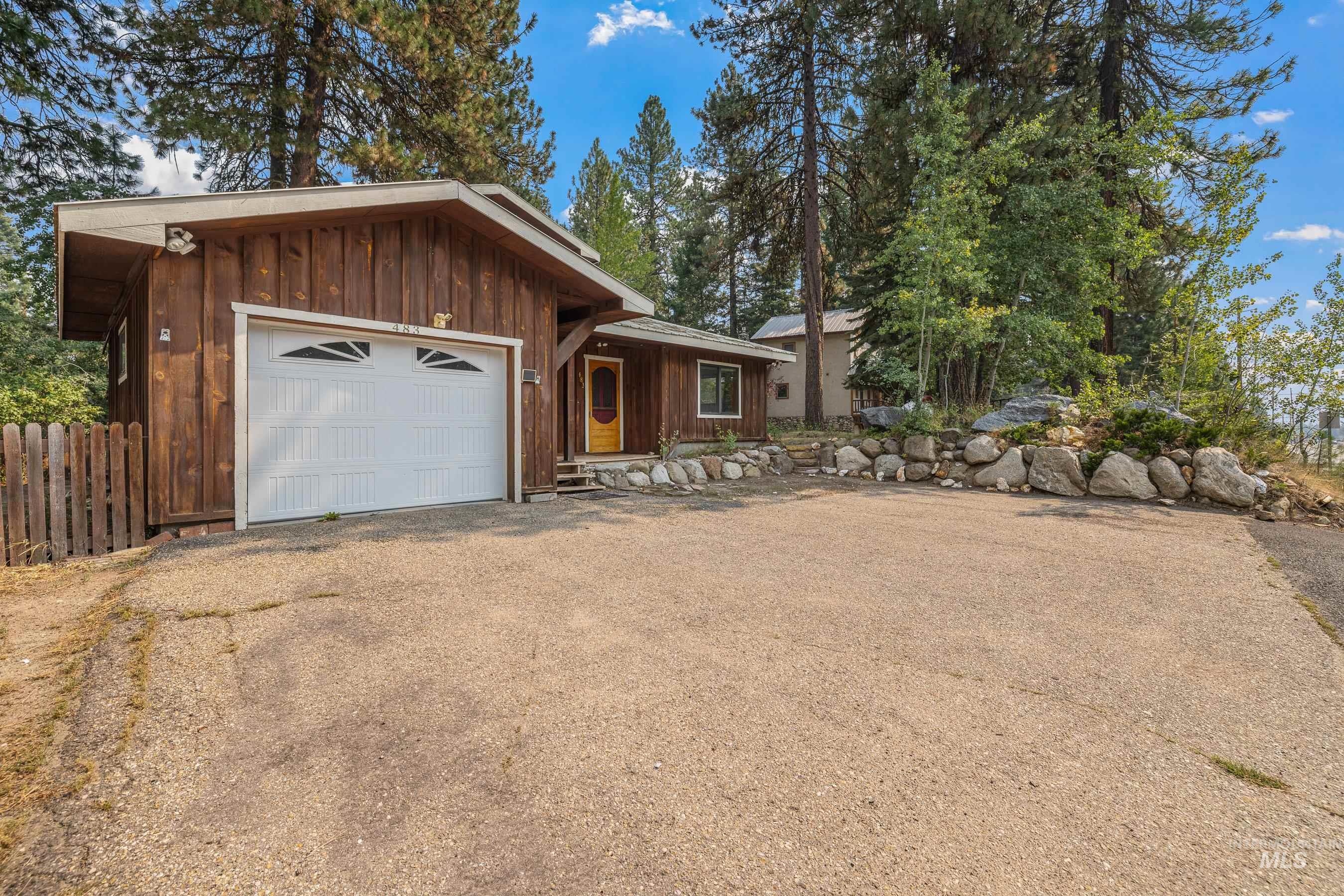 View of front facade featuring board and batten siding, asphalt driveway, and a garage
