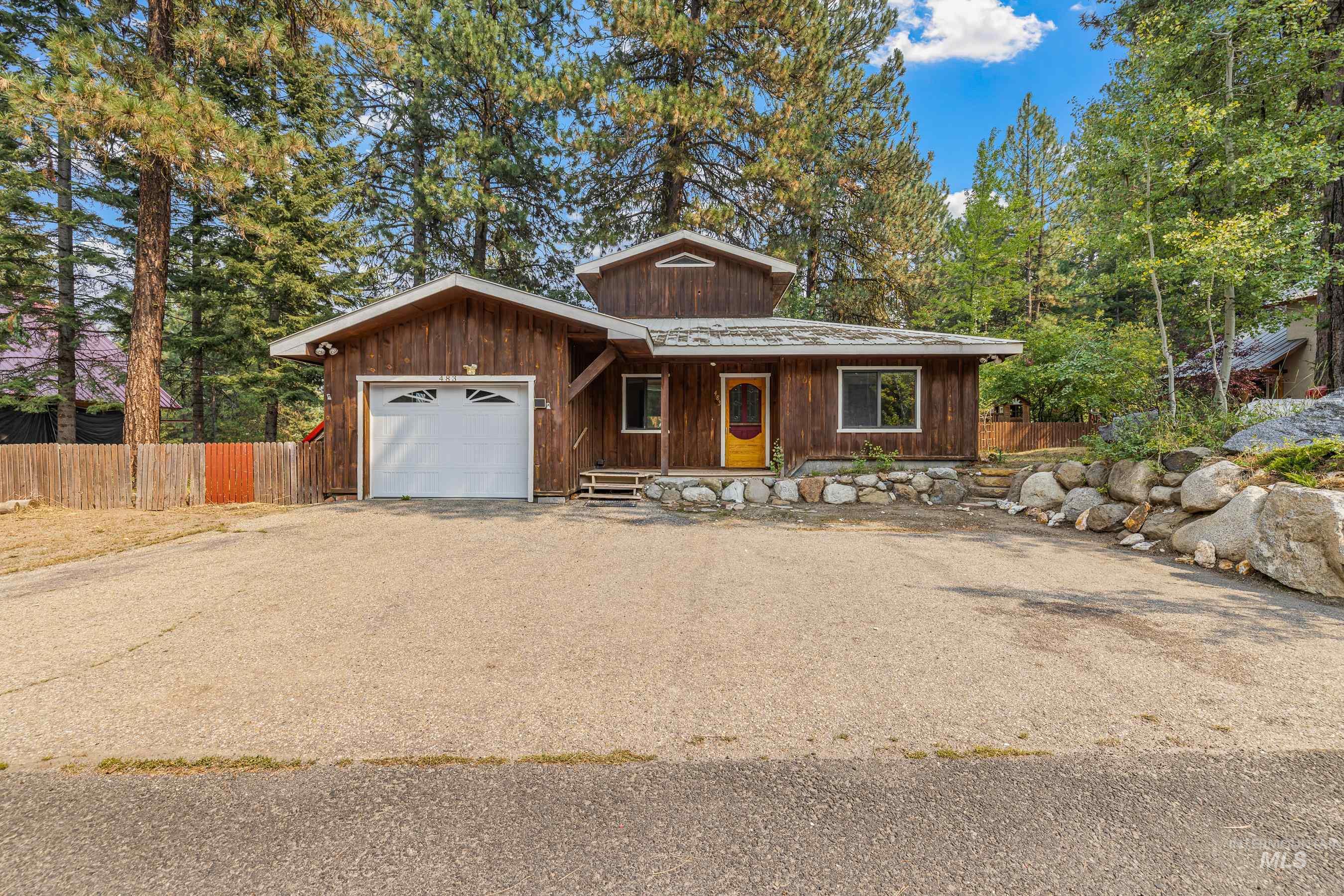 Rustic home with an attached garage, driveway, and covered porch