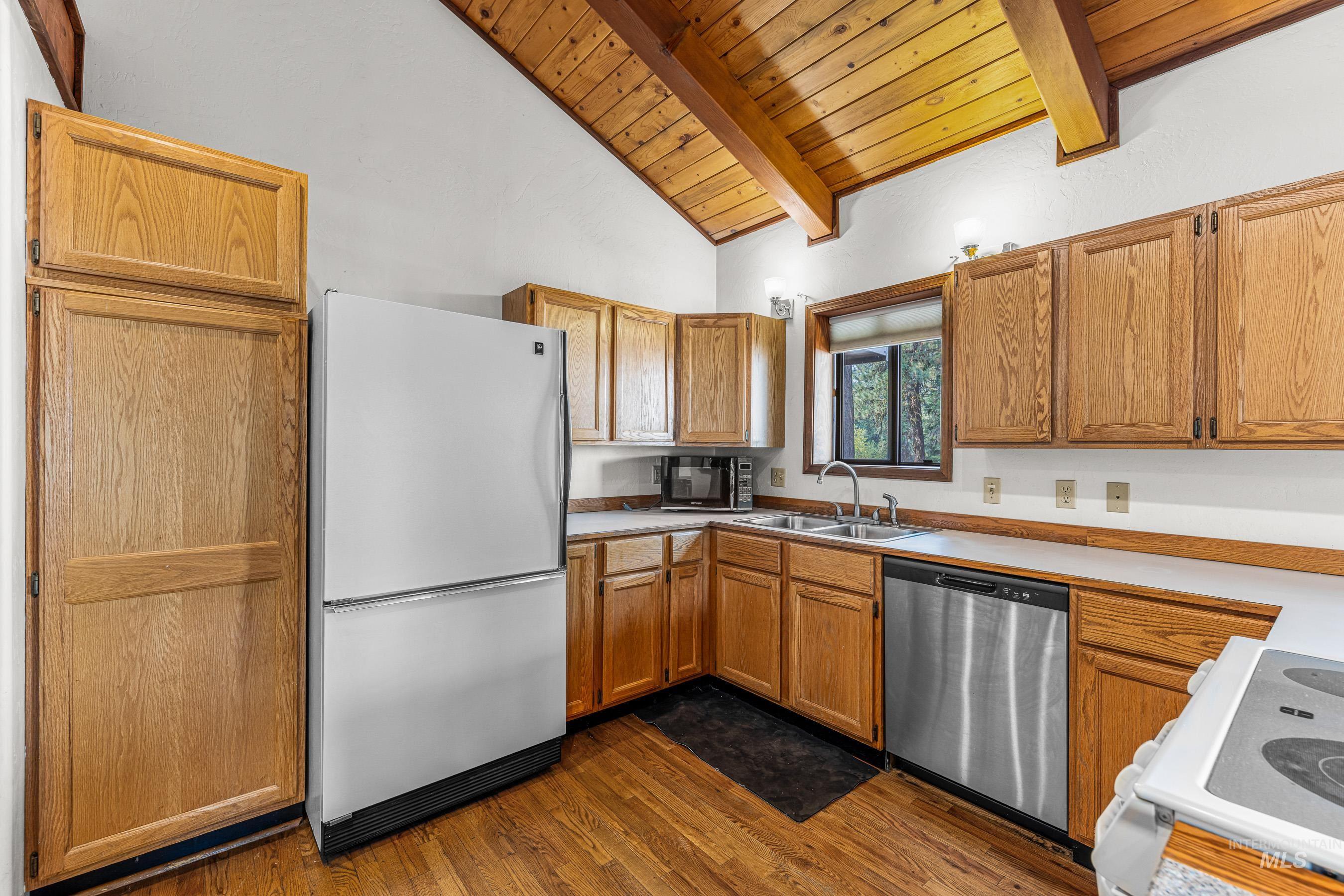 Kitchen with white appliances, light countertops, dark wood-type flooring, wood ceiling, and brown cabinetry