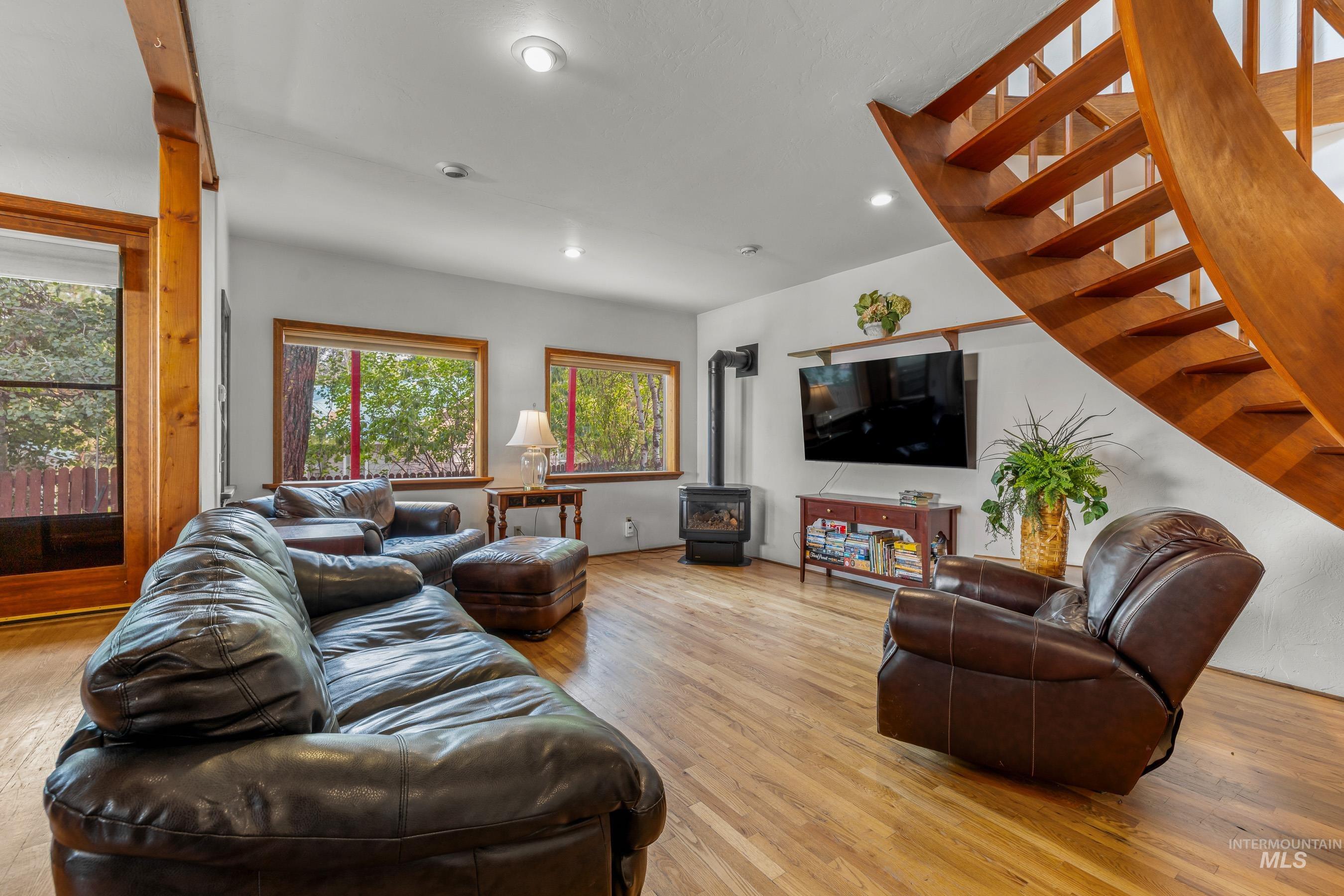 Living area with a wood stove, light wood finished floors, stairway, and recessed lighting
