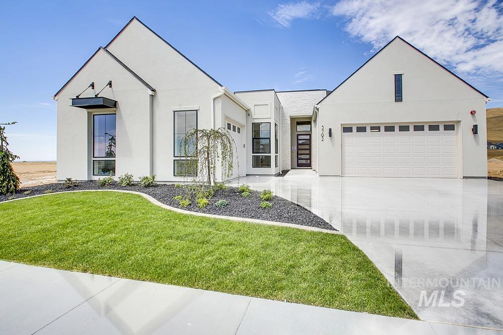 View of front of property featuring stucco siding, driveway, a garage, and a front lawn