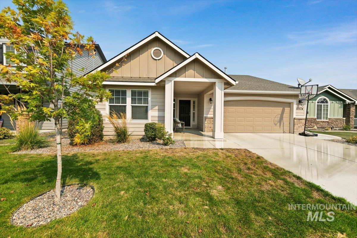 Craftsman house with board and batten siding, a front yard, driveway, and an attached garage