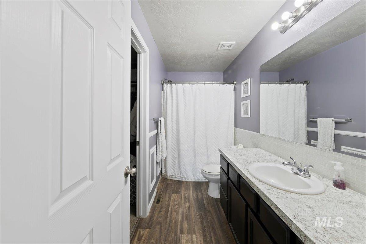 Bathroom featuring vanity, a textured ceiling, dark wood-style floors, and a shower with shower curtain