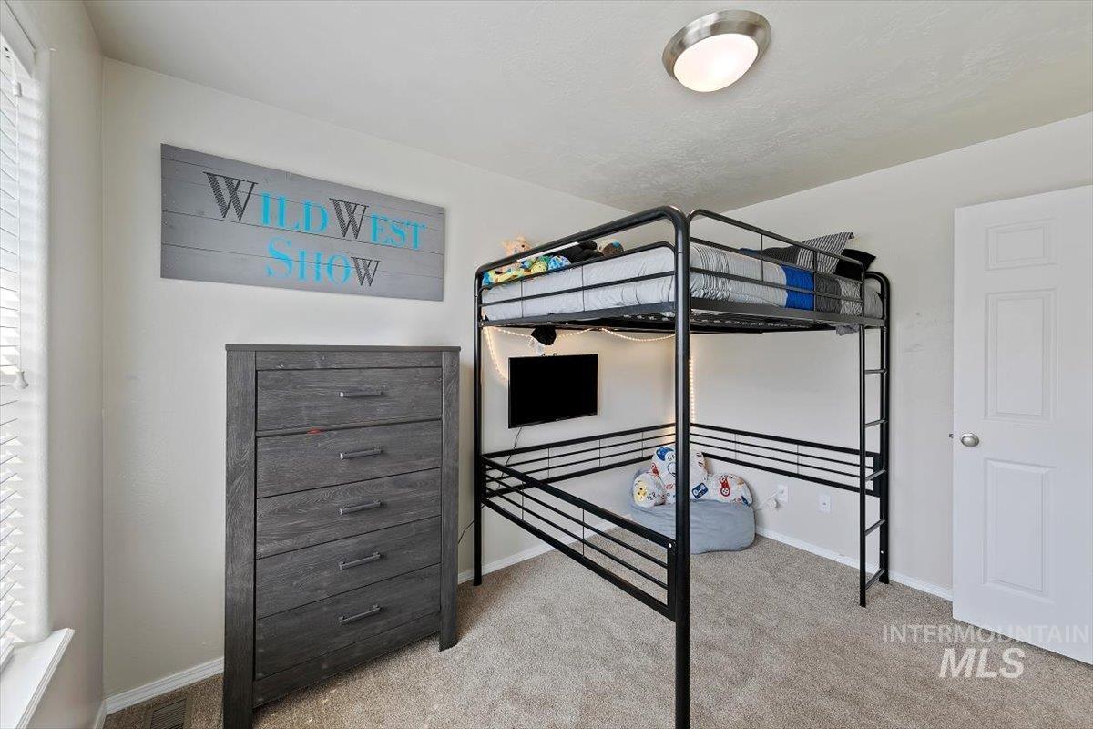 Bedroom featuring light carpet and baseboards