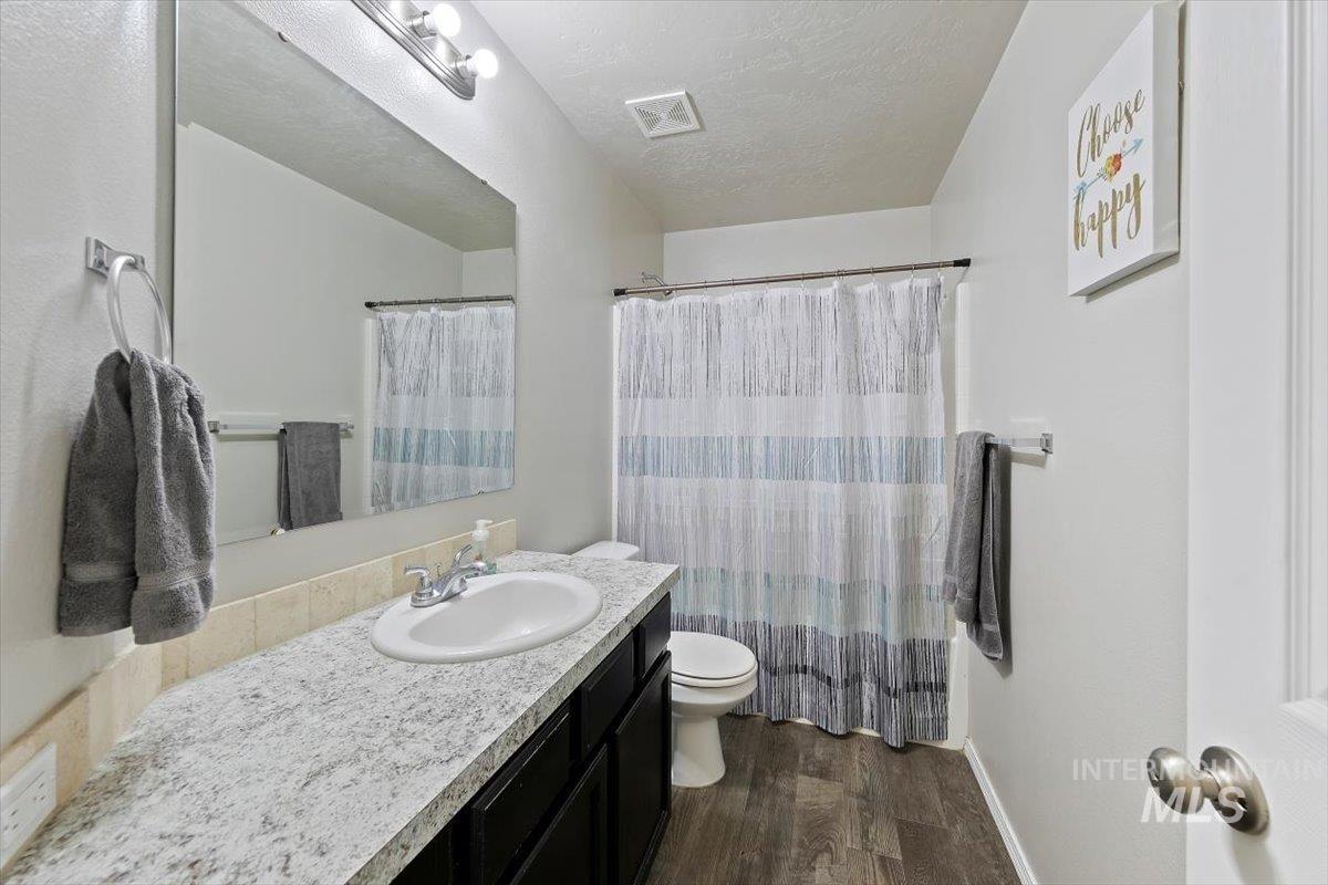 Bathroom with dark wood-type flooring, vanity, a textured ceiling, and a shower with curtain