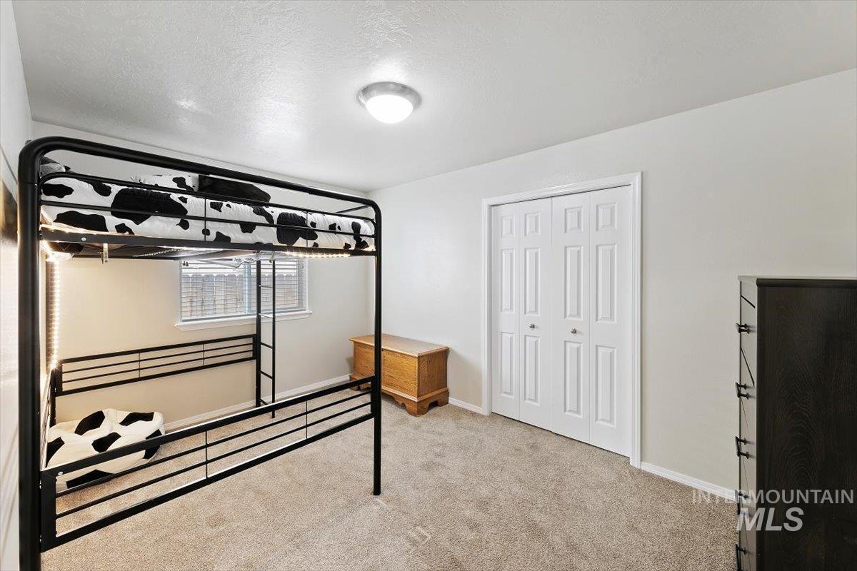 Bedroom featuring light carpet, a textured ceiling, and a closet