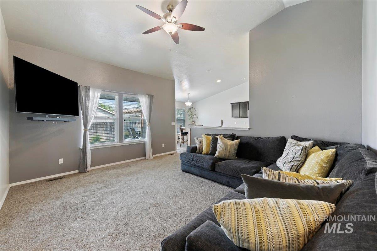 Carpeted living room featuring lofted ceiling and a ceiling fan