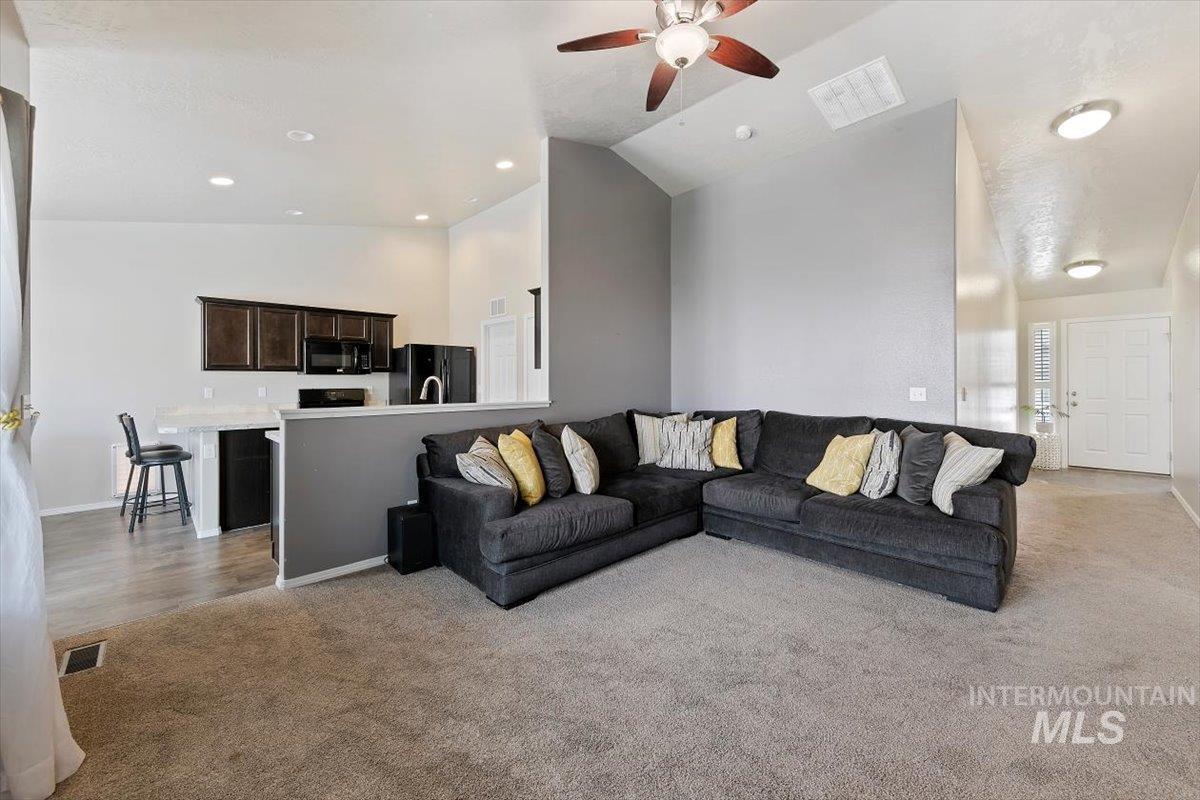 Living area with light colored carpet, high vaulted ceiling, ceiling fan, and recessed lighting