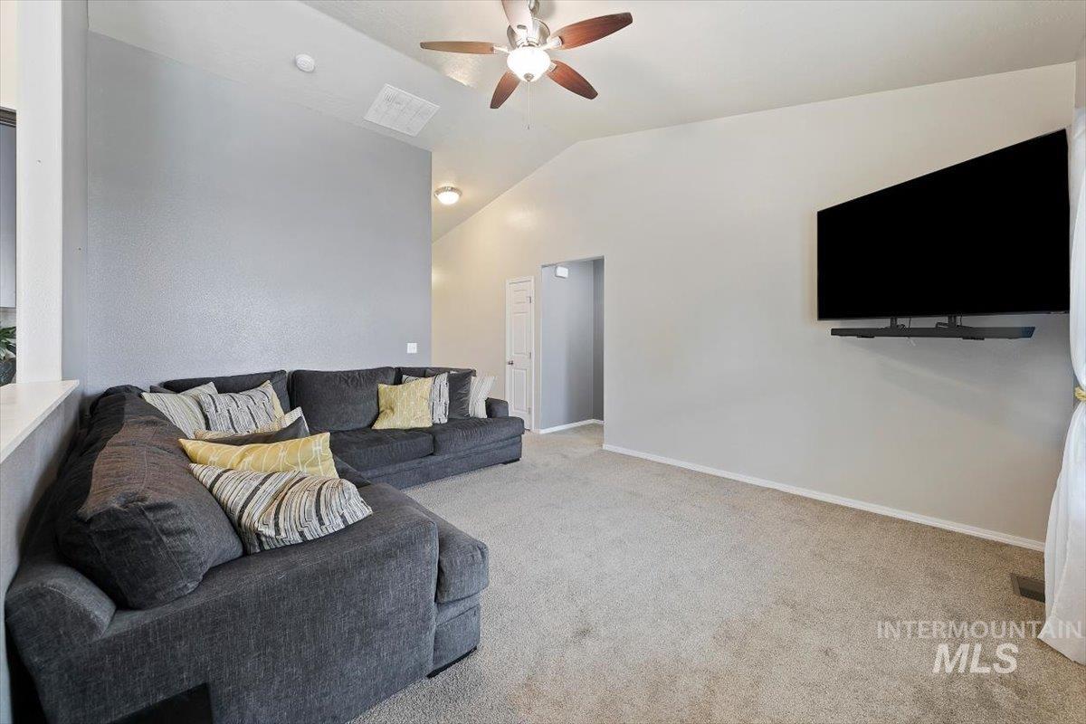 Living room featuring lofted ceiling, light carpet, and a ceiling fan