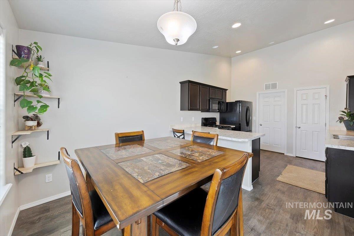 Dining room with dark wood-type flooring and recessed lighting