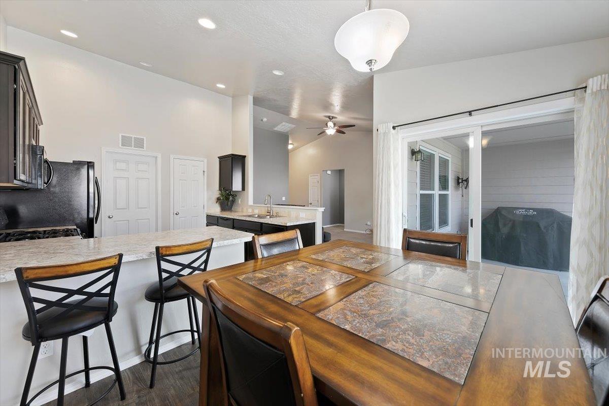 Dining room featuring lofted ceiling, ceiling fan, recessed lighting, and dark wood-style floors