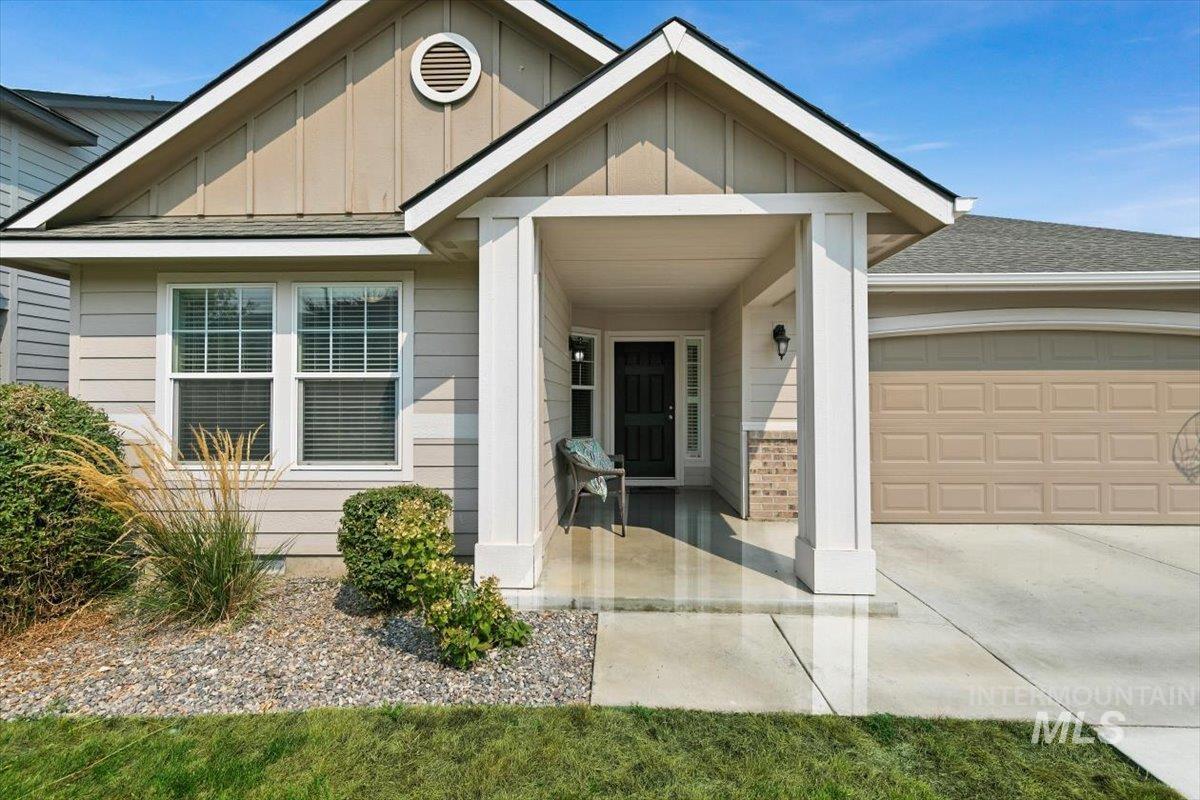 Doorway to property featuring board and batten siding, a shingled roof, an attached garage, and concrete driveway
