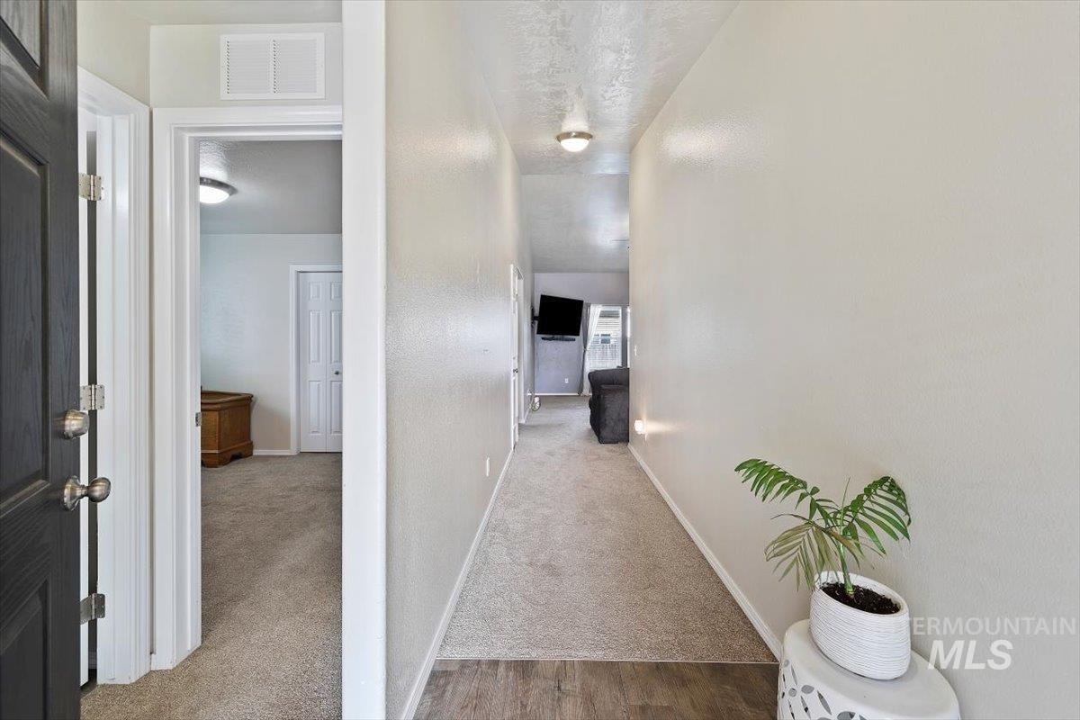 Corridor with light colored carpet and a textured ceiling