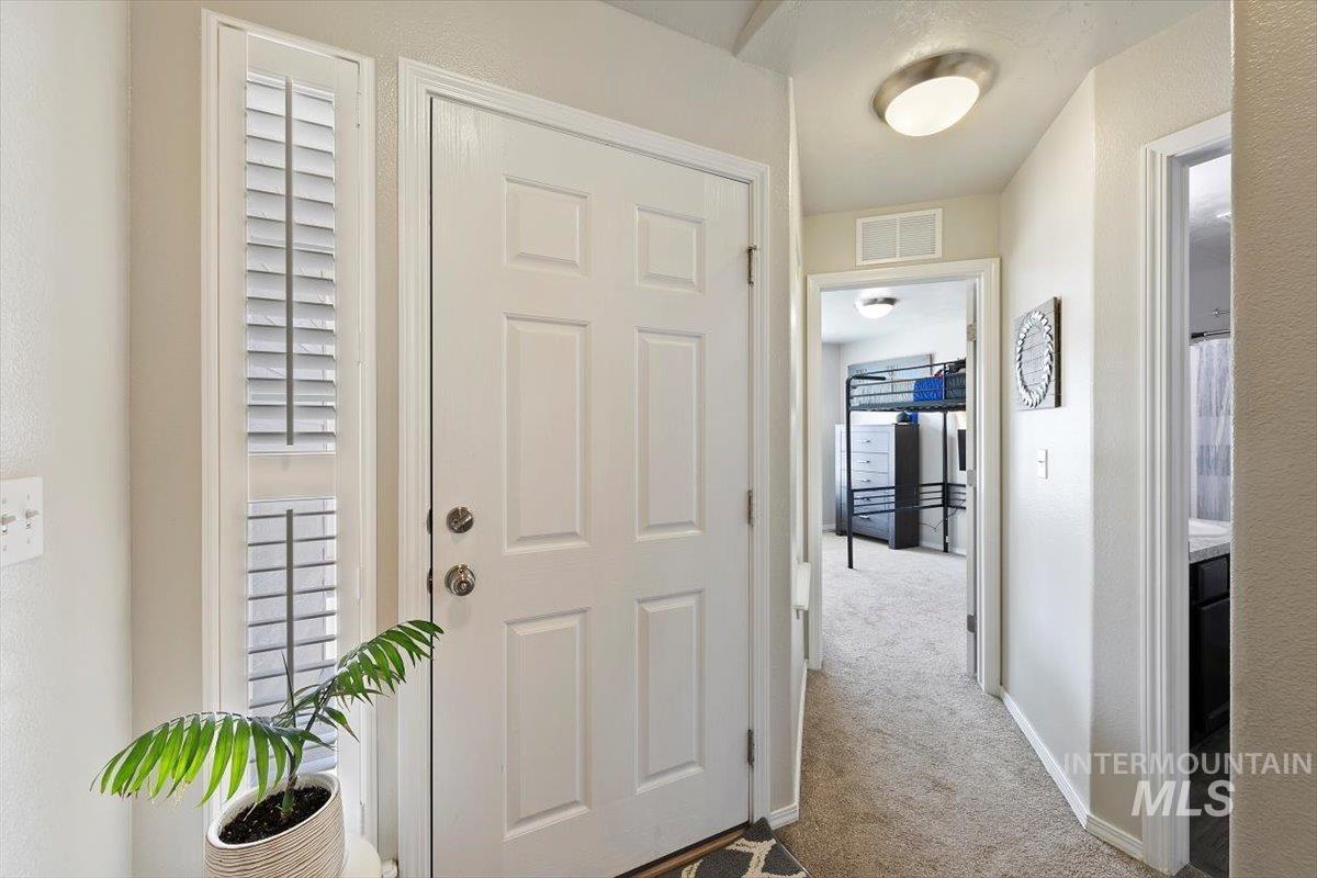 Foyer entrance featuring light carpet and a textured wall