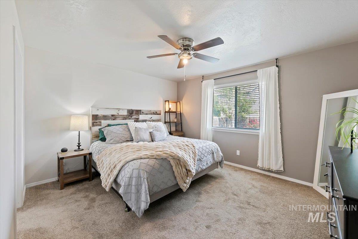 Bedroom featuring light colored carpet, a ceiling fan, and a textured ceiling
