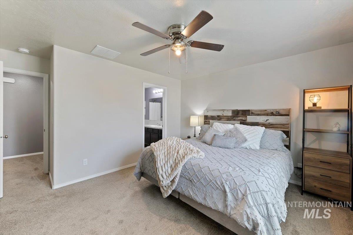 Bedroom featuring light carpet, a ceiling fan, and ensuite bath