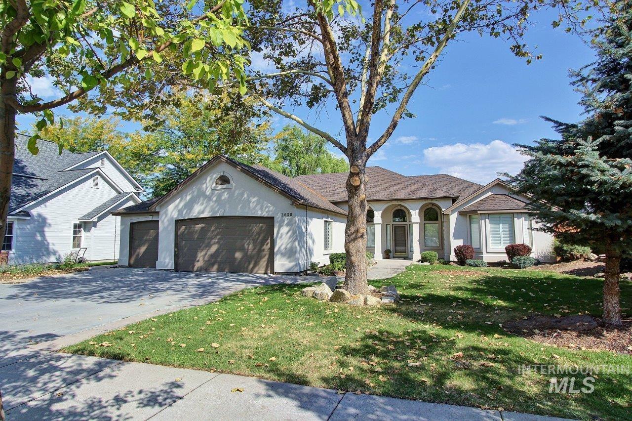 View of front facade with a front lawn, driveway, an attached garage, and stucco siding