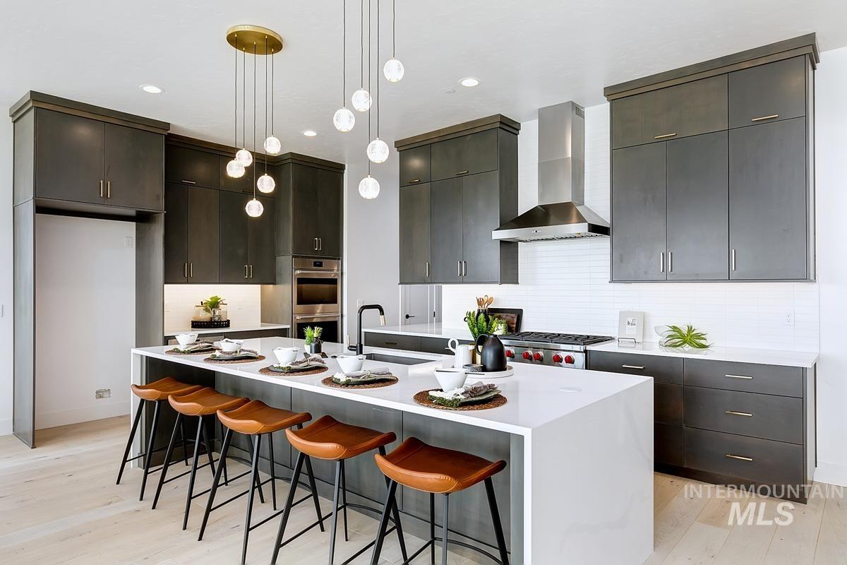 Kitchen featuring a kitchen breakfast bar, tasteful backsplash, pendant lighting, light wood-style flooring, and recessed lighting