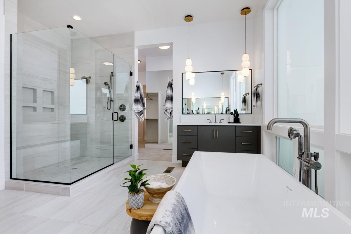 Bathroom featuring vanity, a shower stall, a soaking tub, and light tile patterned flooring
