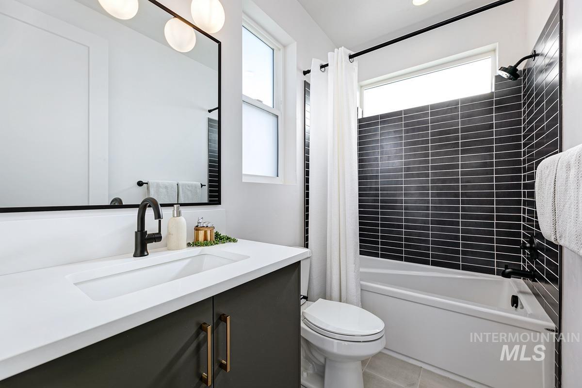Bathroom featuring shower / tub combo, vanity, and light tile patterned floors
