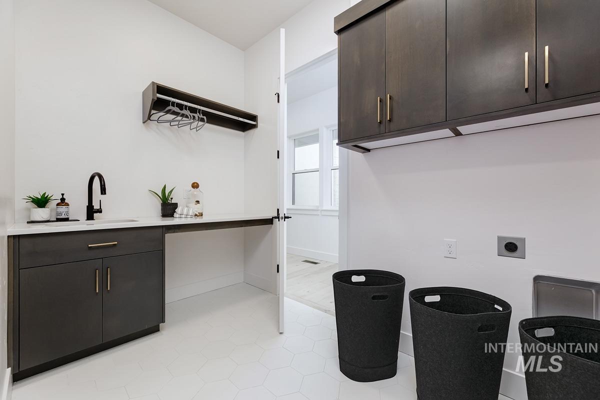 Laundry room featuring electric dryer hookup, cabinet space, and light tile patterned flooring