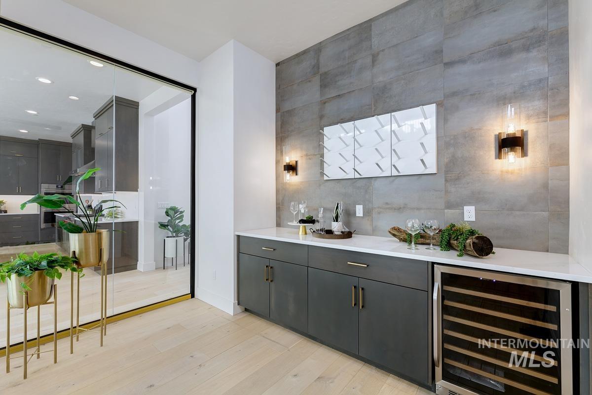 Indoor dry bar featuring beverage cooler, tile walls, light wood-style flooring, gray cabinets, and recessed lighting