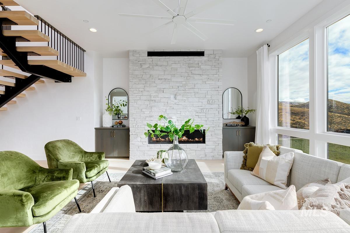 Living area with a stone fireplace, recessed lighting, stairway, and wood finished floors