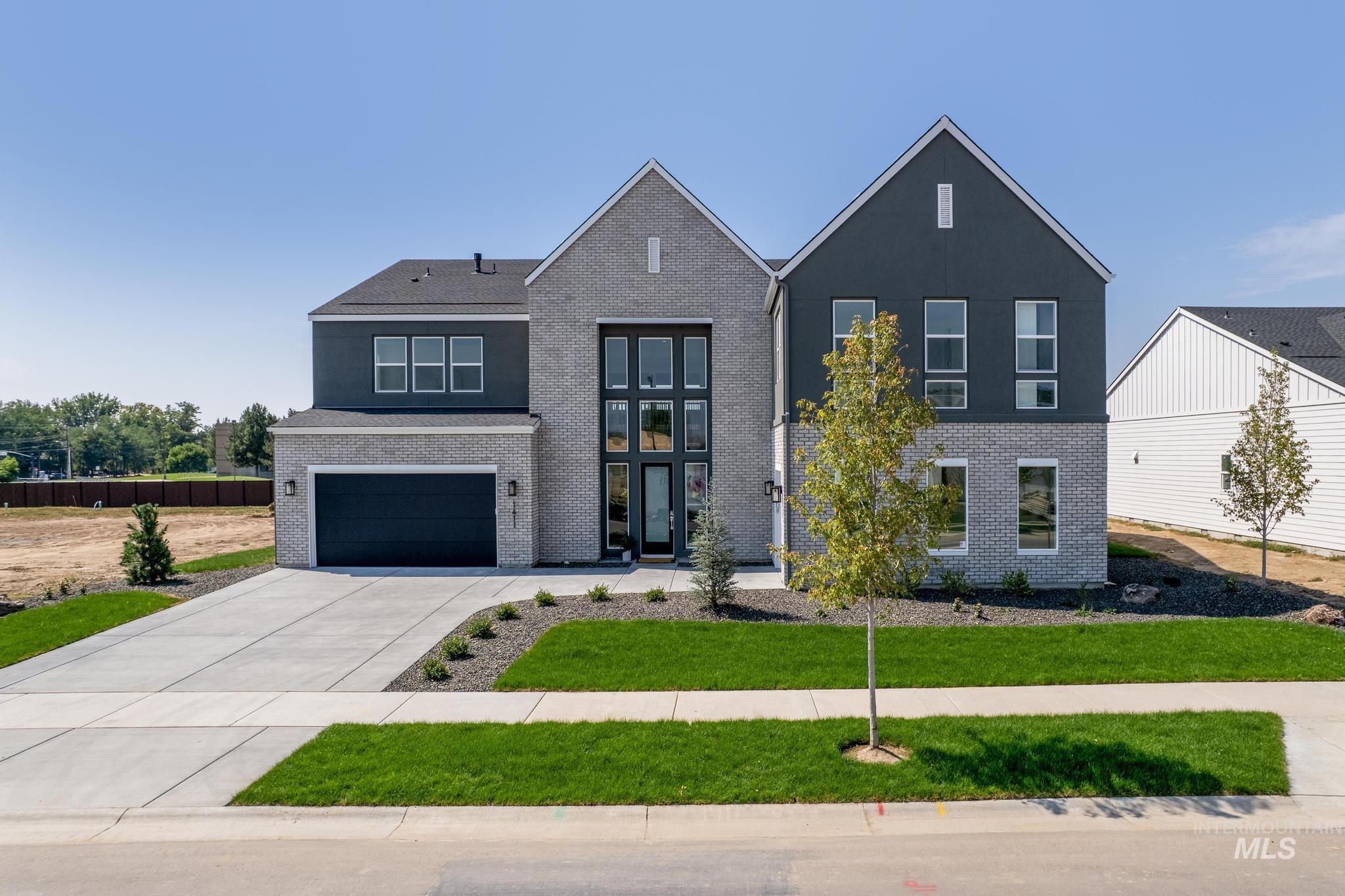 View of front of property with brick siding, concrete driveway, a garage, and a front yard