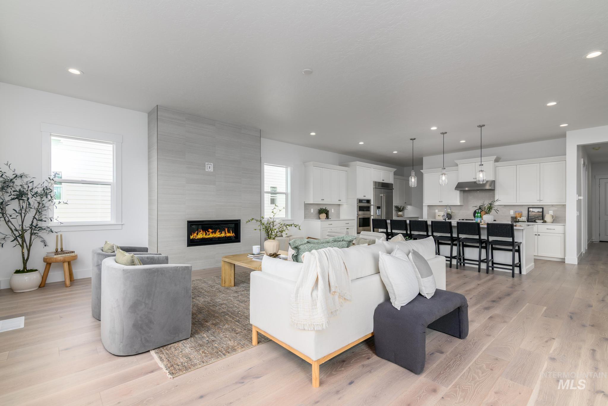 Living area featuring light wood finished floors, a large fireplace, and recessed lighting