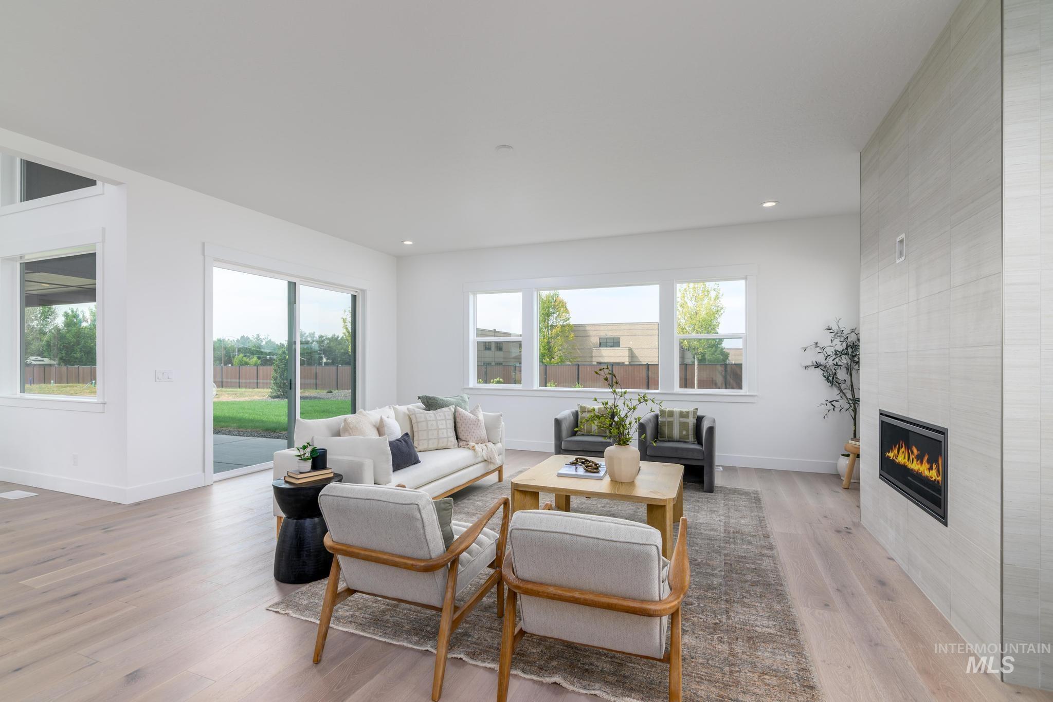 Living room with light wood-style flooring, a tile fireplace, and recessed lighting