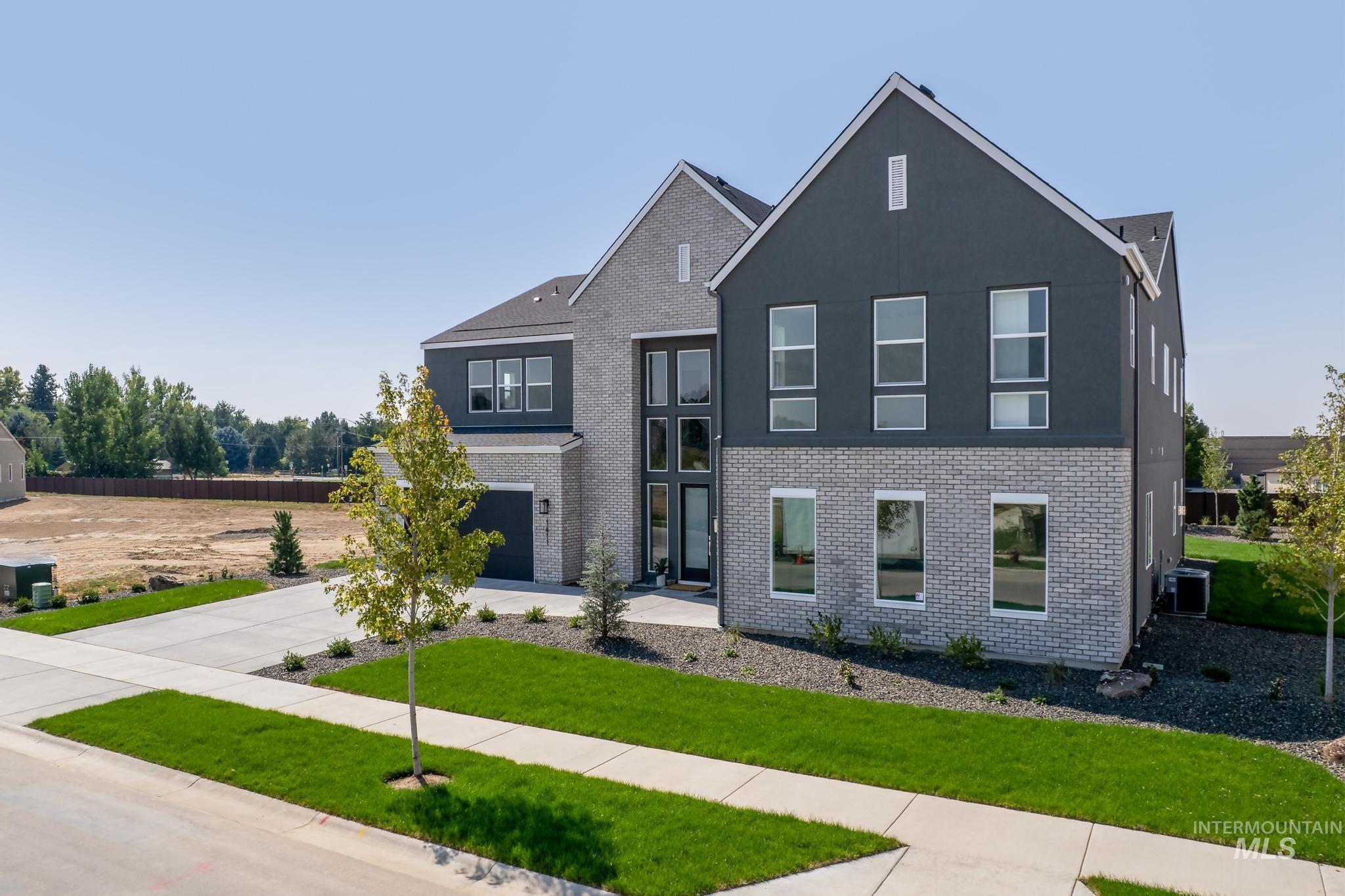 View of front of home with brick siding, driveway, a garage, and stucco siding