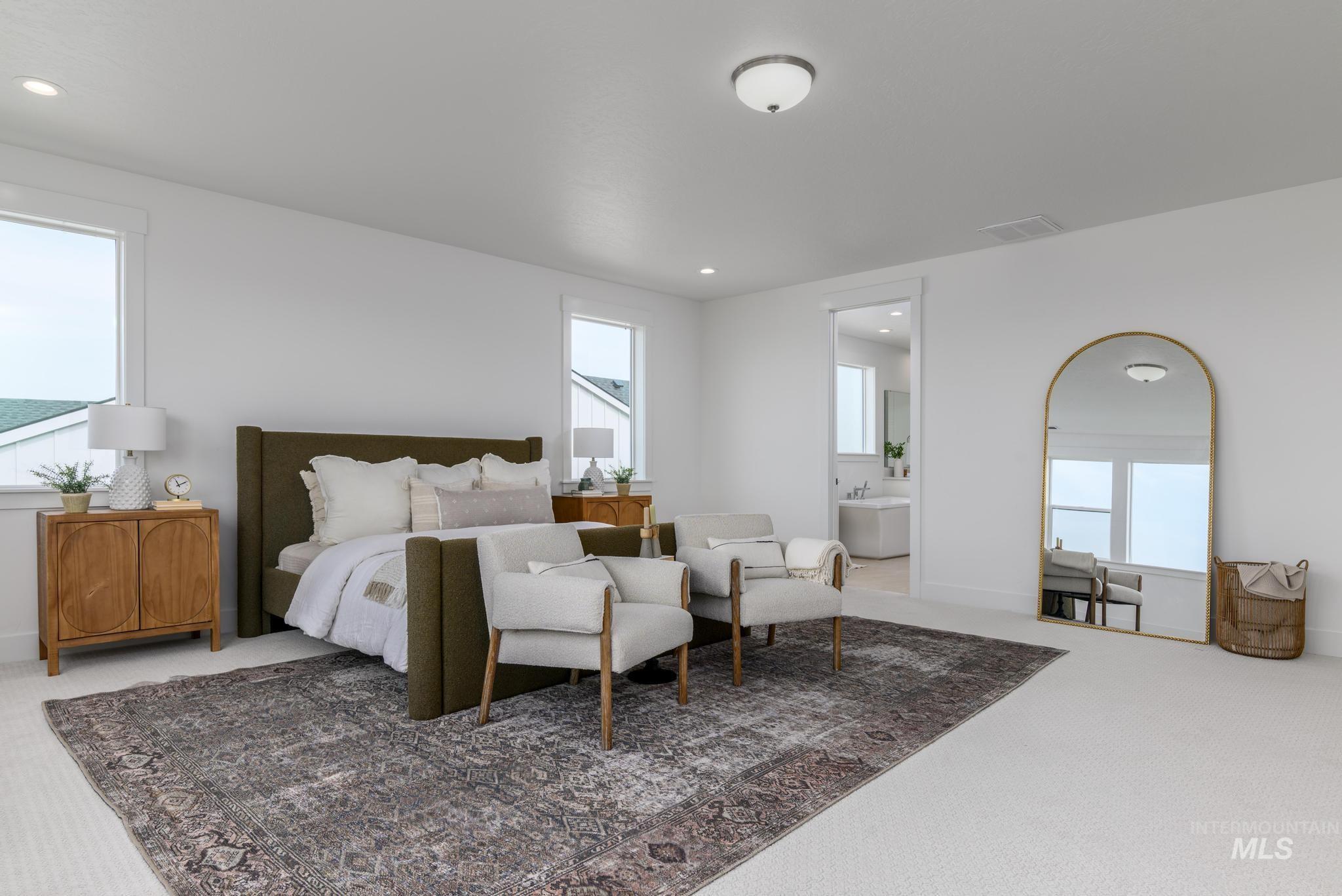Carpeted bedroom with multiple windows, recessed lighting, and ensuite bath