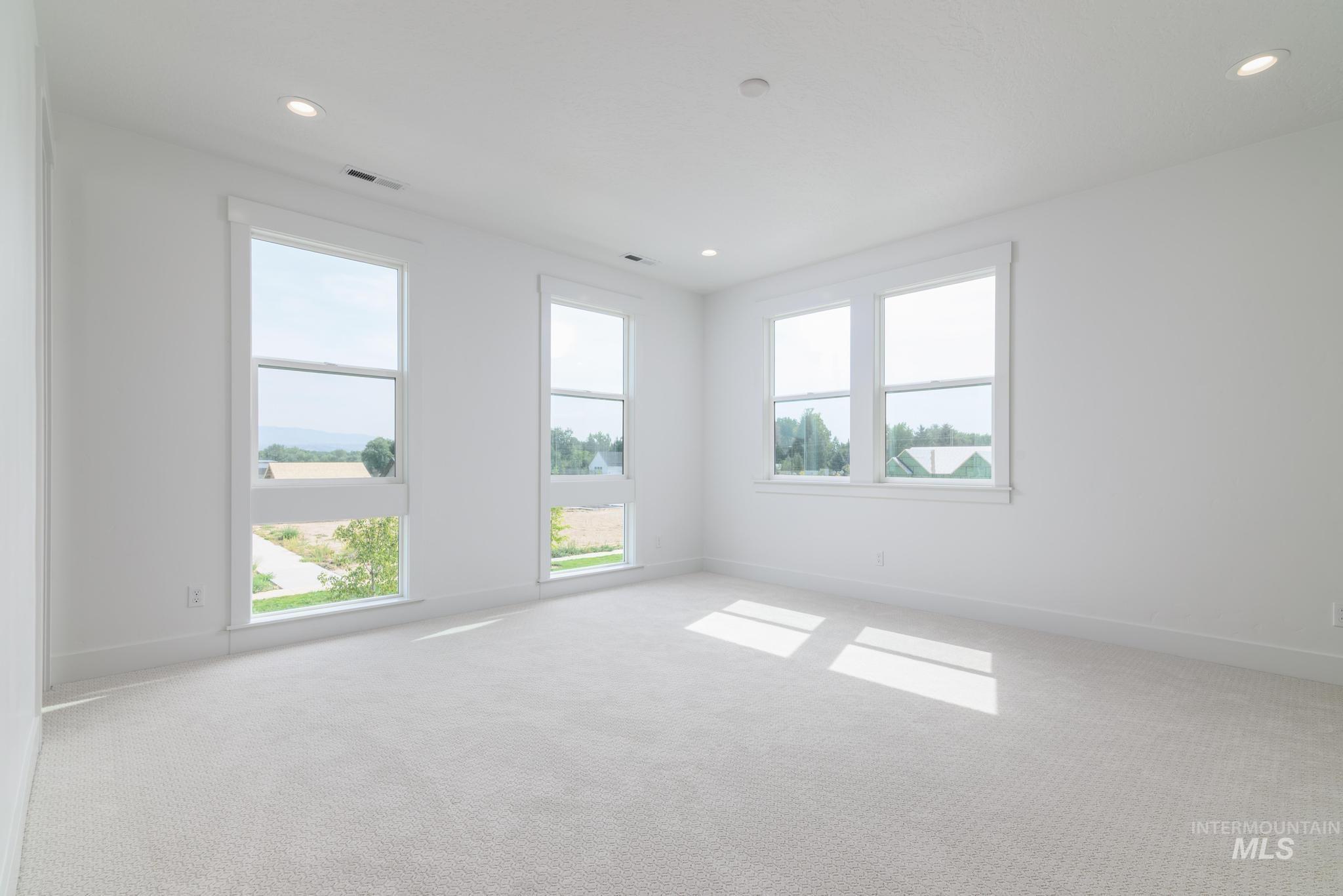 Empty room with plenty of natural light, light colored carpet, and recessed lighting