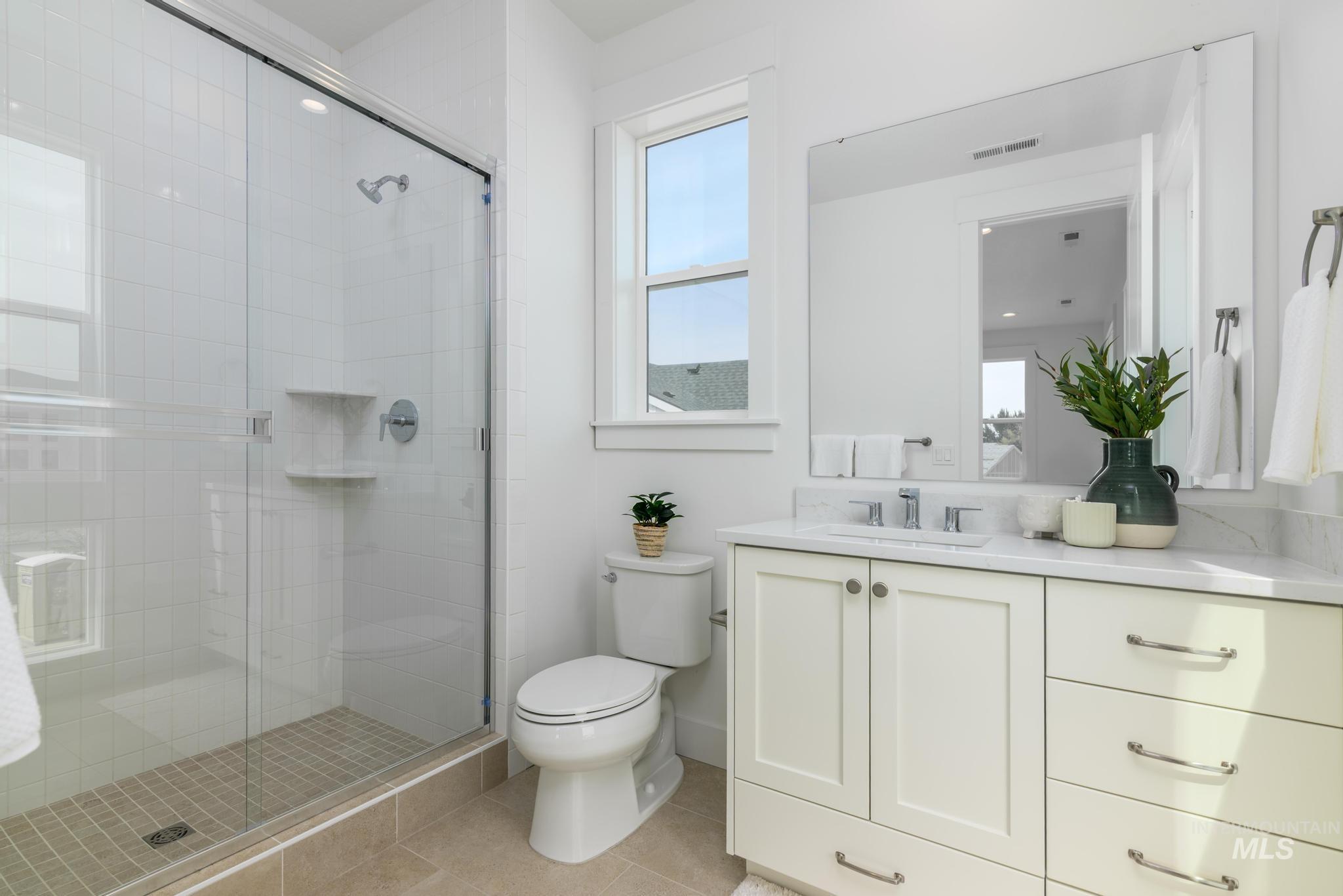 Bathroom with vanity, light tile patterned floors, and a shower stall
