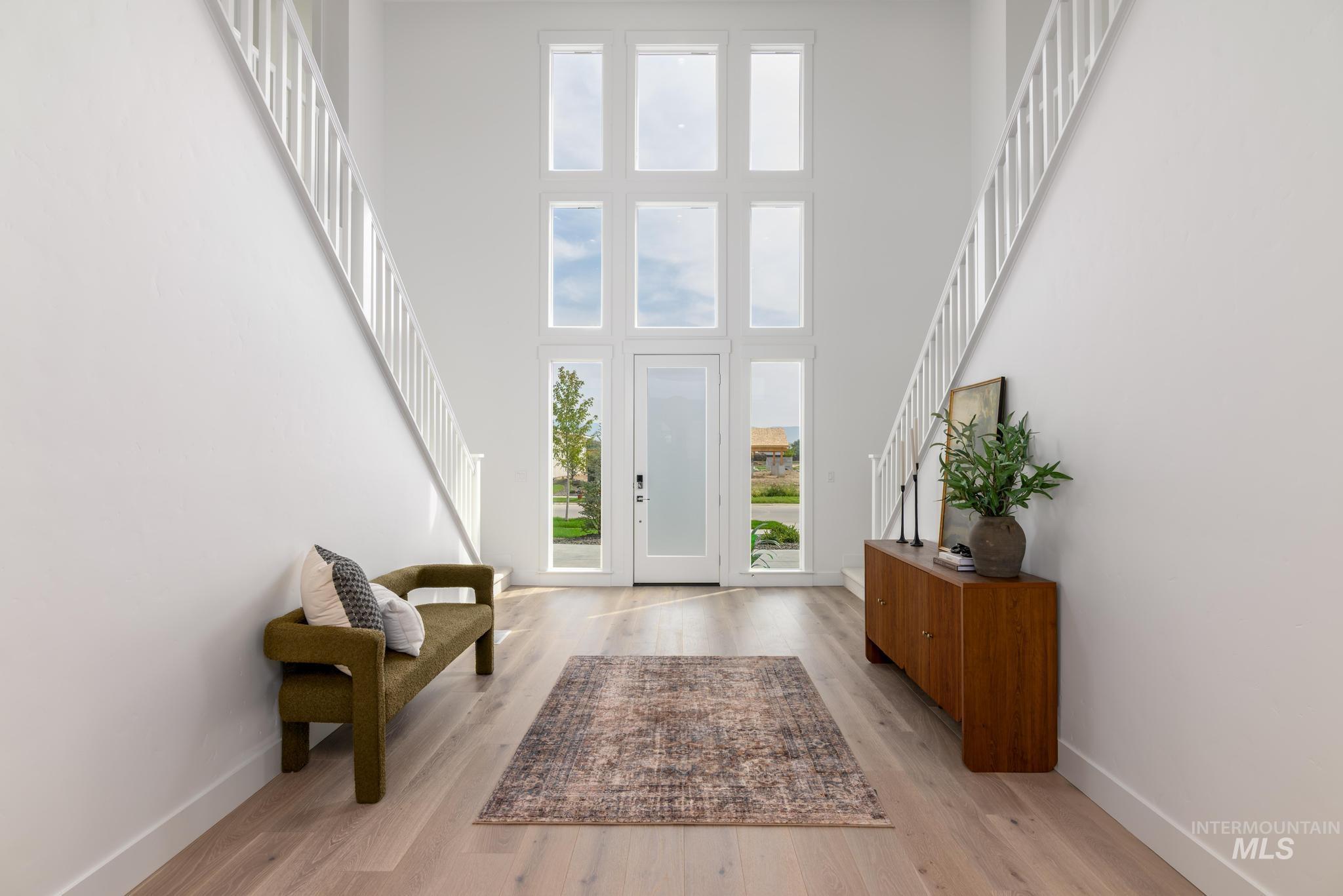Entryway featuring stairway, light wood-style flooring, and a high ceiling