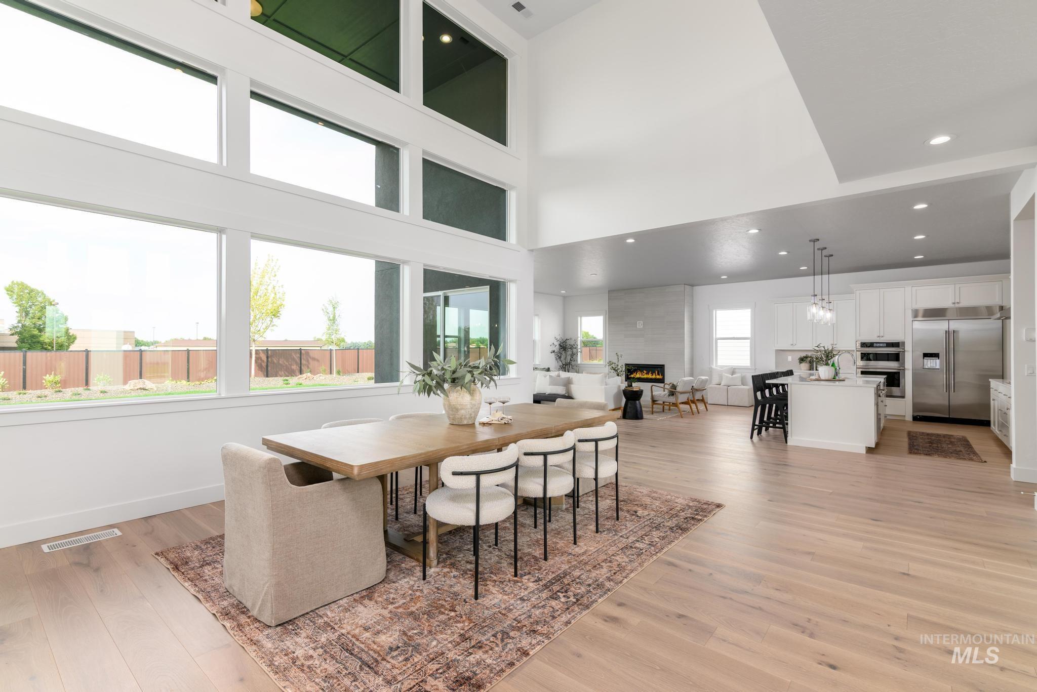 Dining room featuring recessed lighting, light wood-style floors, a towering ceiling, and a large fireplace