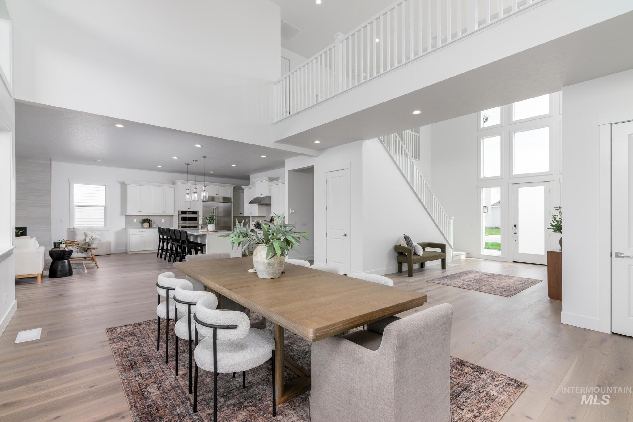 Dining space with stairway, light wood-style flooring, a towering ceiling, and recessed lighting