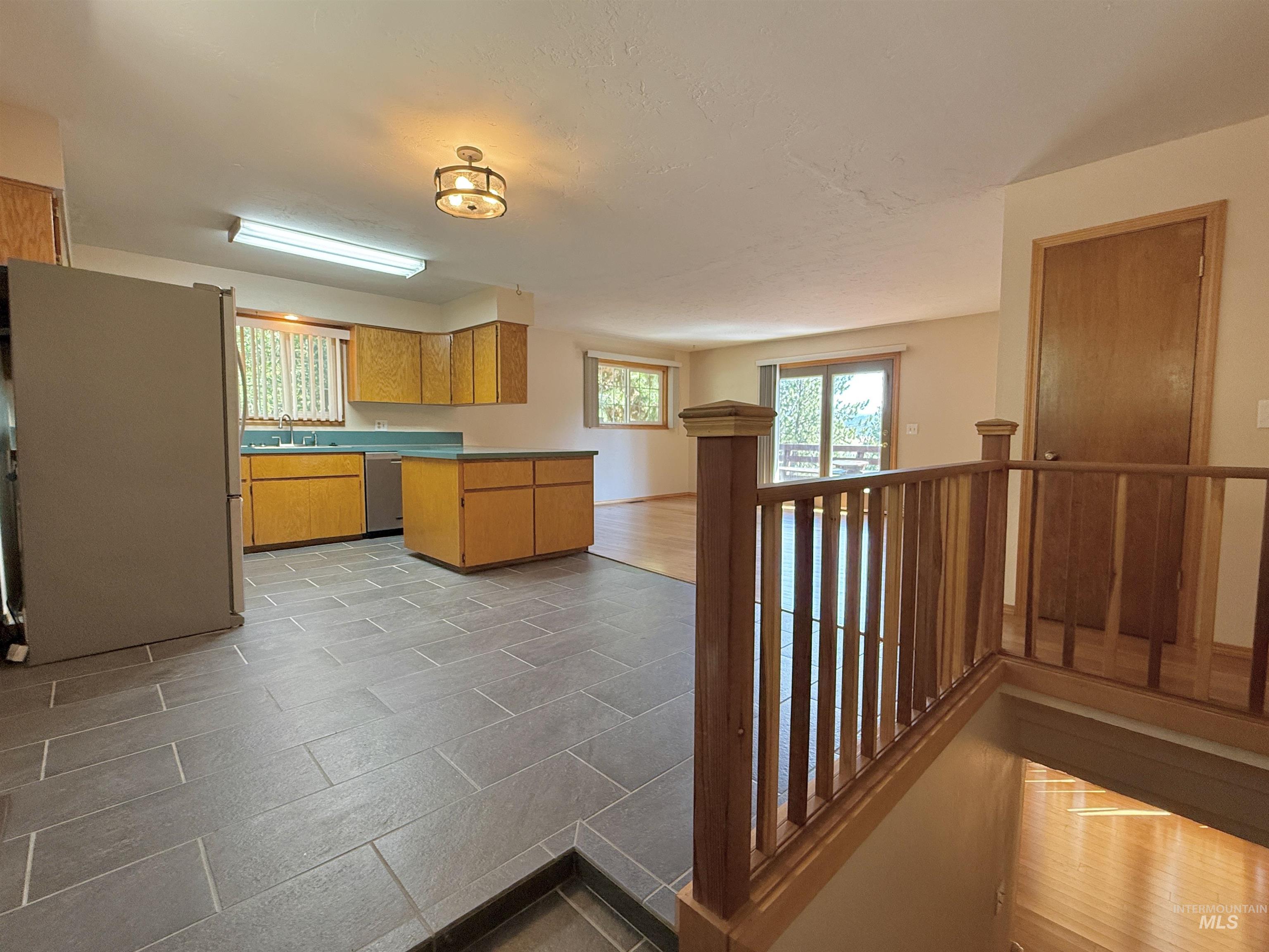 Kitchen featuring freestanding refrigerator, healthy amount of natural light, dishwasher, and a peninsula