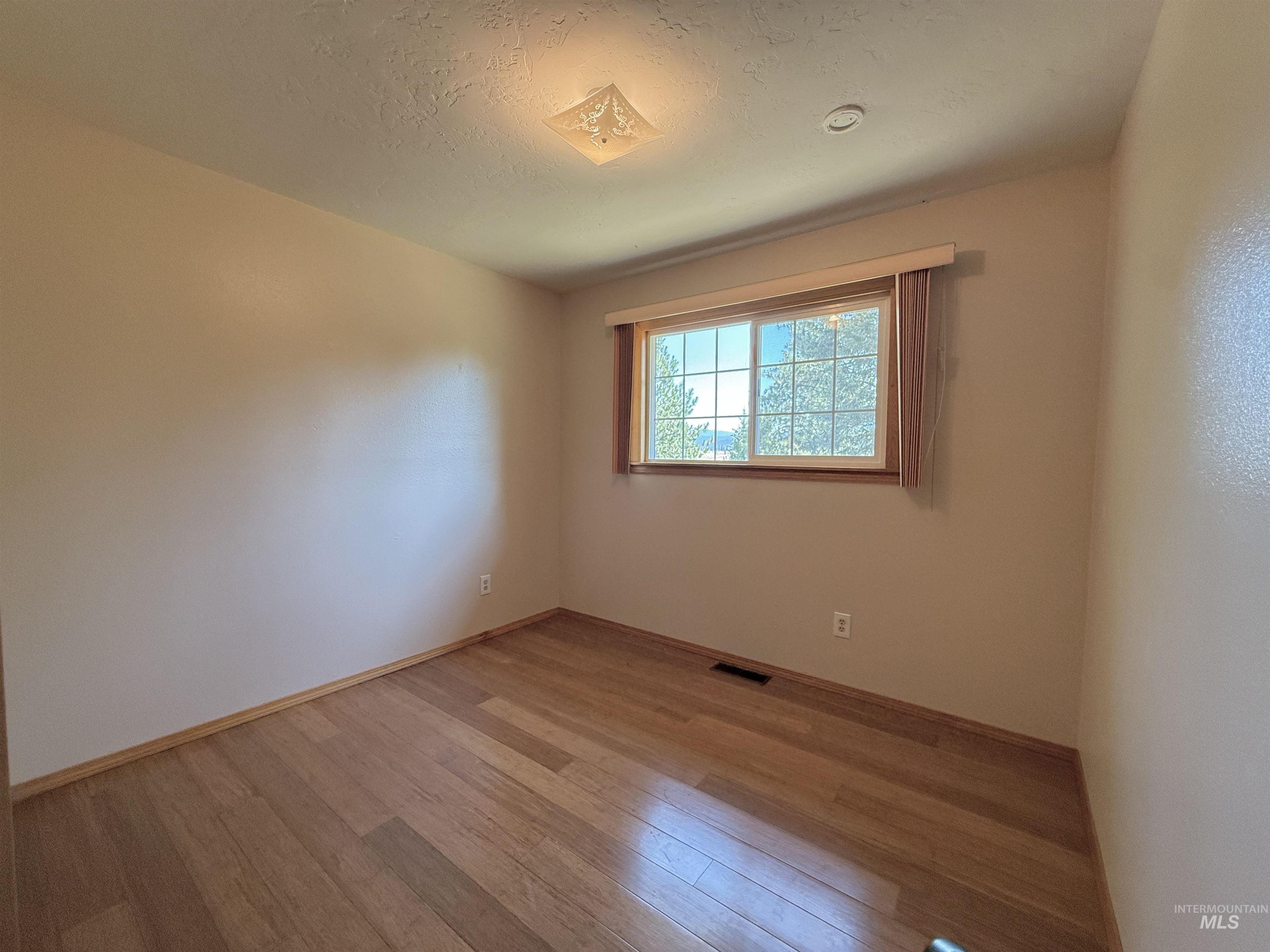 Spare room featuring light wood-type flooring and a textured ceiling